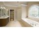 Elegant bathroom with soaking tub, glass shower and decorative arched window at 2049 Kinderton Manor Dr, Johns Creek, GA 30097
