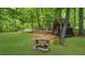 Picturesque backyard featuring a wooden shed, stone fire pit, and a lush lawn surrounded by trees at 2700 Sandstone Dr, Lawrenceville, GA 30043