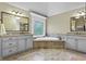 Luxurious bathroom with dual vanities, a large soaking tub, granite countertops, and plenty of natural light at 101 Fernwood Dr, Woodstock, GA 30188