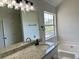 Bathroom featuring a large granite countertop, soaking tub, and framed mirror at 3432 Sumter Pl, Decatur, GA 30034