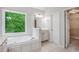 Modern bathroom with tiled floors, garden tub, and a vanity near a large window at 732 Sweet Gum Way, Canton, GA 30115