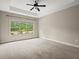 Large bedroom featuring a tray ceiling, a ceiling fan, a large window with natural light and neutral carpeting at 74 Stonegate Ct, Dallas, GA 30157