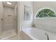 This bright bathroom features a glass shower and separate soaking tub with a view of trees at 1725 Redbud Way, Cumming, GA 30041