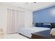 Cozy bedroom featuring a queen bed, blue accent wall, and light-filtering curtains for a relaxing ambiance at 2568 Morning Glory Pl, Lawrenceville, GA 30044