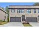 Charming townhome featuring a gray brick facade, a two-car garage, and a well-maintained lawn at 3493 Monarch Ave, Duluth, GA 30096