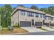 View of townhome featuring gray brick facade, a two-car garage, and a well-maintained lawn at 3493 Monarch Ave, Duluth, GA 30096