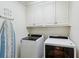 Bright laundry room featuring modern washer and dryer units with white cabinets above for storage at 3672 Haddon Hall Rd, Atlanta, GA 30327