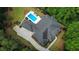 An aerial view of the pool, brick house and expansive manicured grounds with lush trees, a dark gray roof and long driveway at 850 Cog Hl, Mcdonough, GA 30253