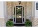 Elegant front door with sidelights, a decorative wreath, and vibrant potted plants at 4800 Gablestone Xing, Hoschton, GA 30548