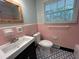 Vintage bathroom featuring pink tile, a white toilet, and patterned tile flooring at 779 Casplan Sw St, Atlanta, GA 30310