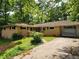Charming single-story brick home featuring a covered parking area and surrounded by lush greenery and mature trees at 1321 Snapfinger Rd, Decatur, GA 30032