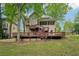 A backyard with house featuring back deck and patio surrounded by trees and green lawn at 2650 Wendell Creek Ln, Snellville, GA 30039