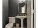 This stylish powder room features dark gray walls, a pedestal sink, and a gold-framed mirror, creating a modern and elegant space at 2656 White Rock Dr, Buford, GA 30519