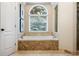 Relaxing primary bathroom featuring a large bathtub with a tile surround and an arched window overlooking the private backyard at 2930 Burnt Hickory Nw Rd, Marietta, GA 30064
