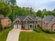 Stunning aerial view of a two-story home with a three-car garage, lush landscaping, and a large driveway at 5595 Timson Ln, Johns Creek, GA 30022