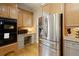 Well lit kitchen with wood floors, wooden cabinets, granite counters and stainless steel refrigerator and black microwave at 5595 Timson Ln, Johns Creek, GA 30022
