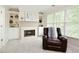 Sitting room with fireplace, built-in cabinets, large window and leather chair at 5595 Timson Ln, Johns Creek, GA 30022