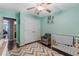 Well-lit Bedroom featuring mint green walls, hardwood floors, patterned rug, crib, and a comfortable chair at 72 Griggs Sw St, Marietta, GA 30064