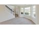 Bright living room with plush carpet, large bay windows, and staircase at 9482 Deer Crossing Ln, Jonesboro, GA 30236