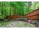 A serene backyard with a wooden fence, lush greenery, a wrought iron bench, and mature trees at 973 Duncan Ter, Canton, GA 30115