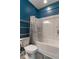 Modern bathroom with blue accent wall, shower-tub combination, and chrome shelving at 360 Winston Cir, Canton, GA 30114
