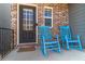 Inviting front porch with brick facade, black door, and blue rocking chairs create a relaxing entry at 360 Winston Cir, Canton, GA 30114