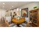 Dining room features modern lighting and adjoins kitchen with stainless steel appliances and white cabinets at 120 Maple Creek Way, Woodstock, GA 30188