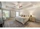 Spacious main bedroom featuring a tray ceiling, ceiling fan, and large windows for ample natural light at 120 Maple Creek Way, Woodstock, GA 30188