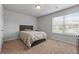 Sunlit bedroom with a wooden bed frame, plush carpet, and a bright window at 279 Sturry Dr, Mcdonough, GA 30252