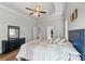 Bright bedroom with tray ceilings, a ceiling fan, wood floors, and a black dresser with mirror at 279 Sturry Dr, Mcdonough, GA 30252