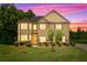 Inviting two-story home with manicured lawn, mature trees, and colorful sunset sky at 279 Sturry Dr, Mcdonough, GA 30252