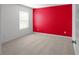 Cozy bedroom features bright red wall and neutral carpet, illuminated by natural light from a window at 435 Noblewood Dr, Mcdonough, GA 30252