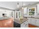 Well-designed kitchen featuring white cabinets, an island, hardwood floors and seamless living room transition at 920 Pebblestone Ct, Alpharetta, GA 30009