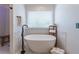 Soaking tub with stylish fixtures and natural light from the large window in a luxurious bathroom at 1004 Spruce Creek Ln, Lawrenceville, GA 30045