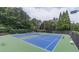 A well-maintained community tennis court featuring new surfacing and lighting surrounded by lush trees at 1004 Spruce Creek Ln, Lawrenceville, GA 30045