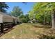 Grassy backyard with a patio and a view of neighboring homes through the trees at 250 Hembree Rd, Roswell, GA 30075