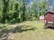 Large fenced backyard with mature trees, grassy lawn and wood deck with access to the home at 7371 Ovis Ct, Riverdale, GA 30274