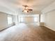 Open living room area with carpeted floors, large windows, and ceiling fan at 5584 Dendy Trce, Fairburn, GA 30213