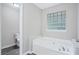 Modern bathroom with a soaking tub, glass block window, light gray walls, and tile flooring at 4872 Lewis Rd, Powder Springs, GA 30127