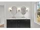 Bright bathroom featuring a double sink vanity with a marble countertop, oval mirrors with sconces, and a window at 1835 Hawkins Se St, Smyrna, GA 30080
