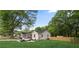 Exterior view of a bright house with a car parked nearby, green grass, and tall mature trees at 1835 Hawkins Se St, Smyrna, GA 30080