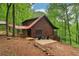 Cozy log cabin with red roof, wooden deck, and patio seating amidst lush green trees at 2361 Mann Rd, Douglasville, GA 30134