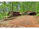 Exterior view of a cozy log cabin home with covered parking and connecting walkway amidst lush trees at 2361 Mann Rd, Douglasville, GA 30134