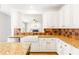 Bright kitchen with white cabinets, granite countertops, farmhouse sink, and stylish tile backsplash at 1342 Winborn Nw Cir, Kennesaw, GA 30152