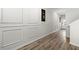 Elegant hallway features wood flooring, decorative wall panels, and stylish artwork leading to a bright doorway at 7492 Knoll Hollow Rd, Lithonia, GA 30058