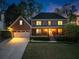 Inviting two-story brick home with a well-lit front porch and landscaped front yard at twilight at 2040 Parliament Dr, Lawrenceville, GA 30043