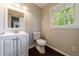 Bathroom with a white vanity, mirror, toilet, wood floors and a window overlooking the outdoors at 3803 Butternut Dr, Decatur, GA 30034