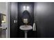 Stylish powder room with a pedestal sink, unique mirror, and contemporary dark accent wall create a modern look at 404 Wade Creek Rd, Alpharetta, GA 30009