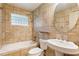 Bathroom with bathtub, neutral-toned tiles, and classic pedestal sink at 975 Shirley Se St, Smyrna, GA 30082
