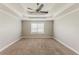 A light and airy bedroom features a tray ceiling with fan, a window and neutral carpeting at 51 Legend Creek Way, Douglasville, GA 30134